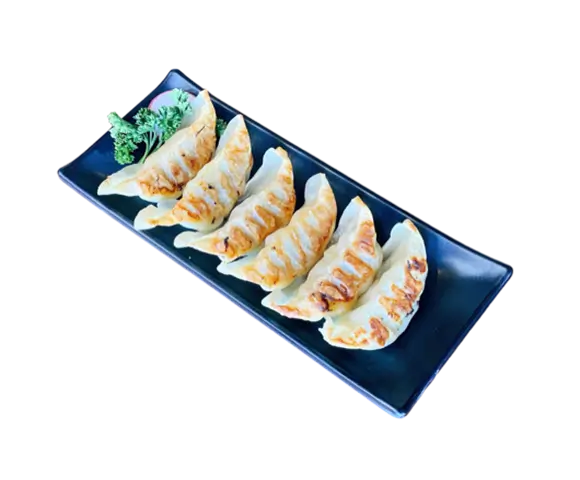 Gyoza are pan-fried dumplings filled with ground meat and vegetables, served with a side of dipping sauce and garnished with parsley at Torakichi Ramen, a Japanese Ramen restaurant in Palm Springs